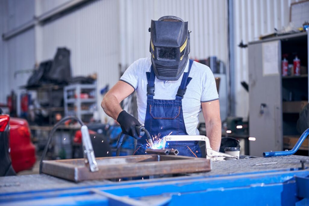 male worker in welding helmet welding metal