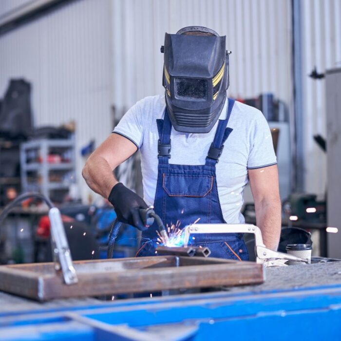 male worker in welding helmet welding metal
